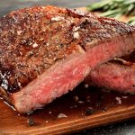 medium rare Rib-Eye-Steak auf Schneidebrett aus Holz
